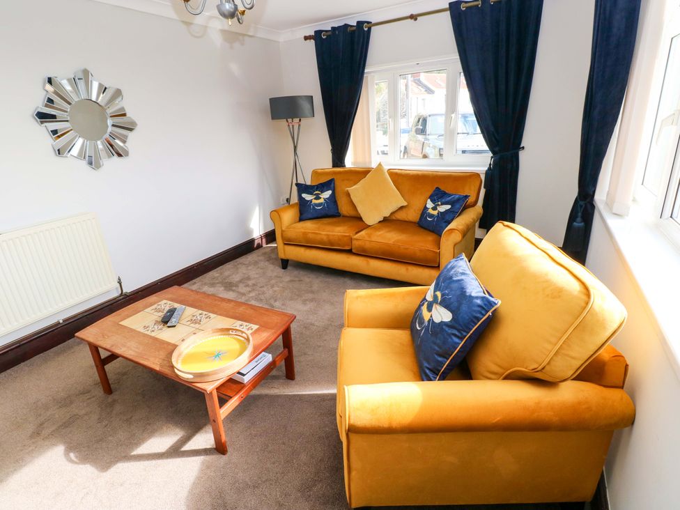 A living room with yellow furniture and a mirror at Graig Goch in Burry Port