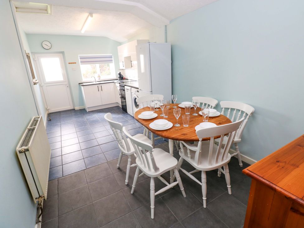 A kitchen with a dining area featuring a table and chairs at Graig Goch in Burry Port