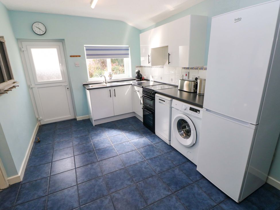 A kitchen with appliances and a door at Graig Goch in Burry Port