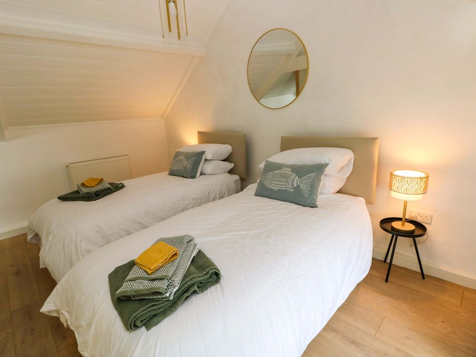 A bedroom with two beds and a bedside lamp at Graig Goch Burry Port