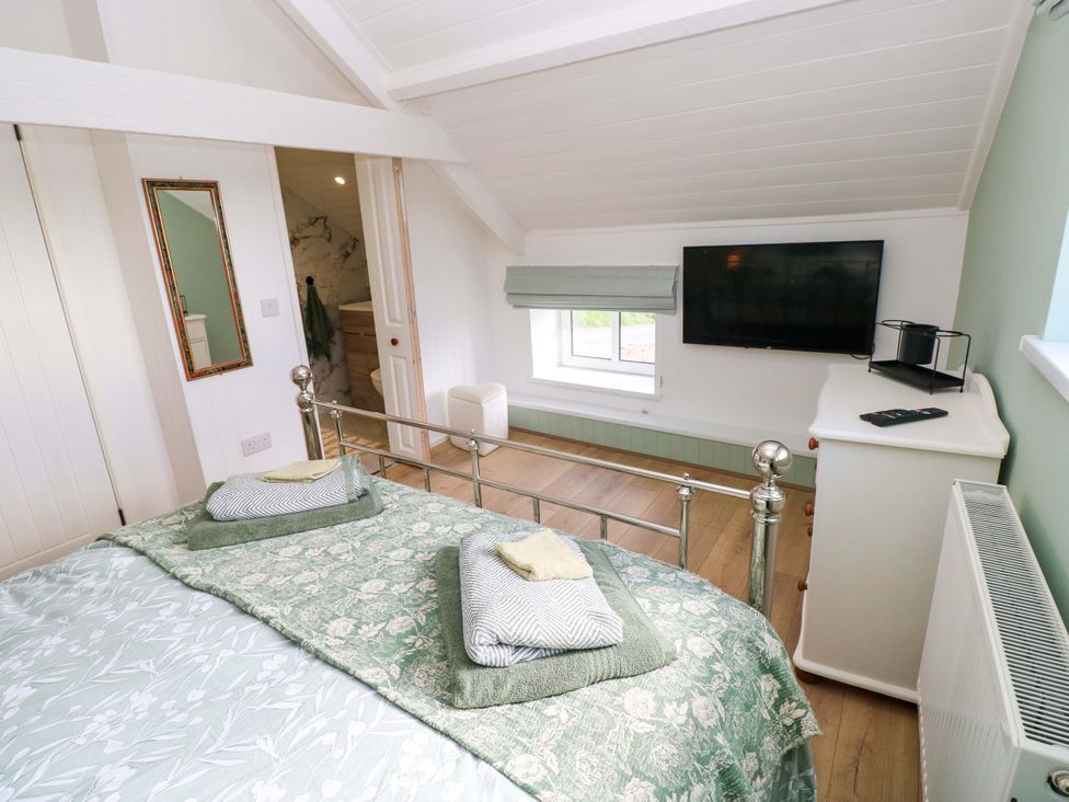 A bedroom with a bed and television at Graig Goch in Burry Port