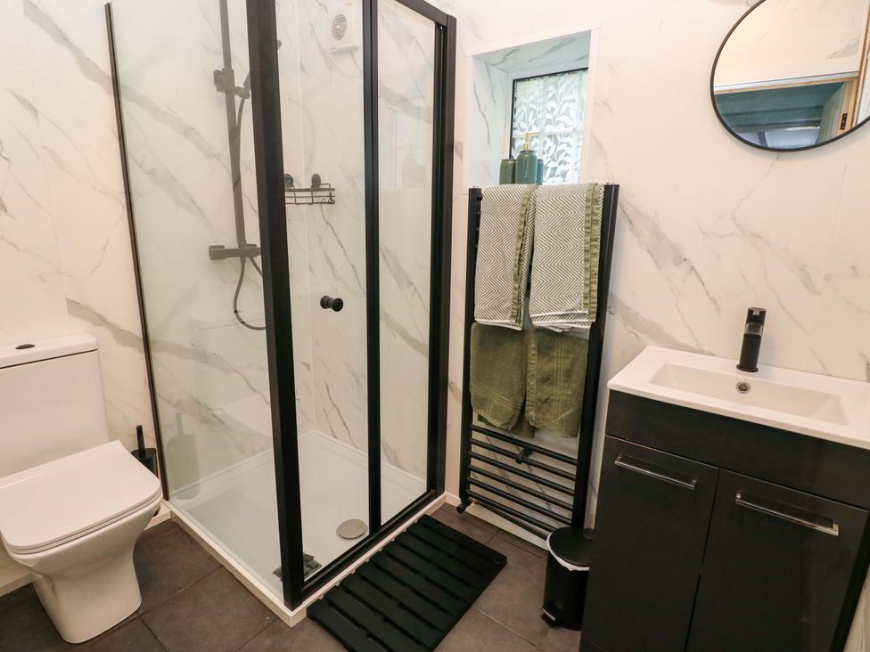 A bathroom with a shower, toilet, sink, and towel rack at Graig Goch Burry Port