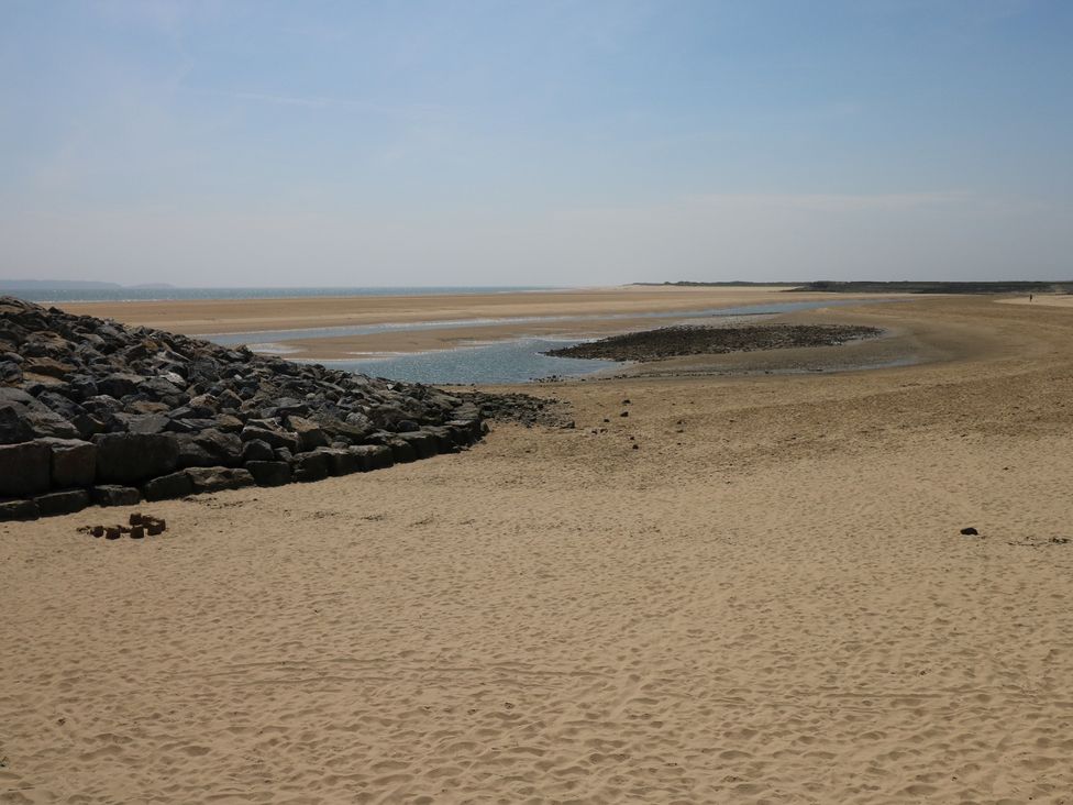 A view of a beach with sand and water at Graig Goch in Burry Port