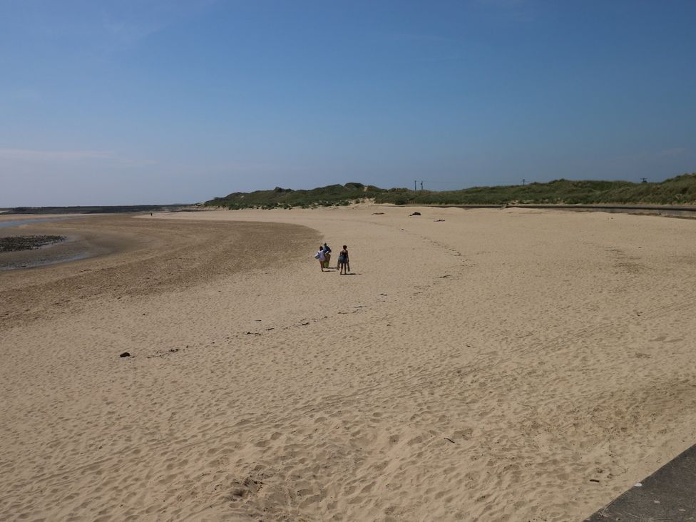A beach with people walking on the sand at Graig Goch in Burry Port