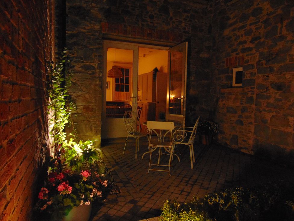An outdoor patio with a seating set and flower pot at Captains Cottage in Donaghadee
