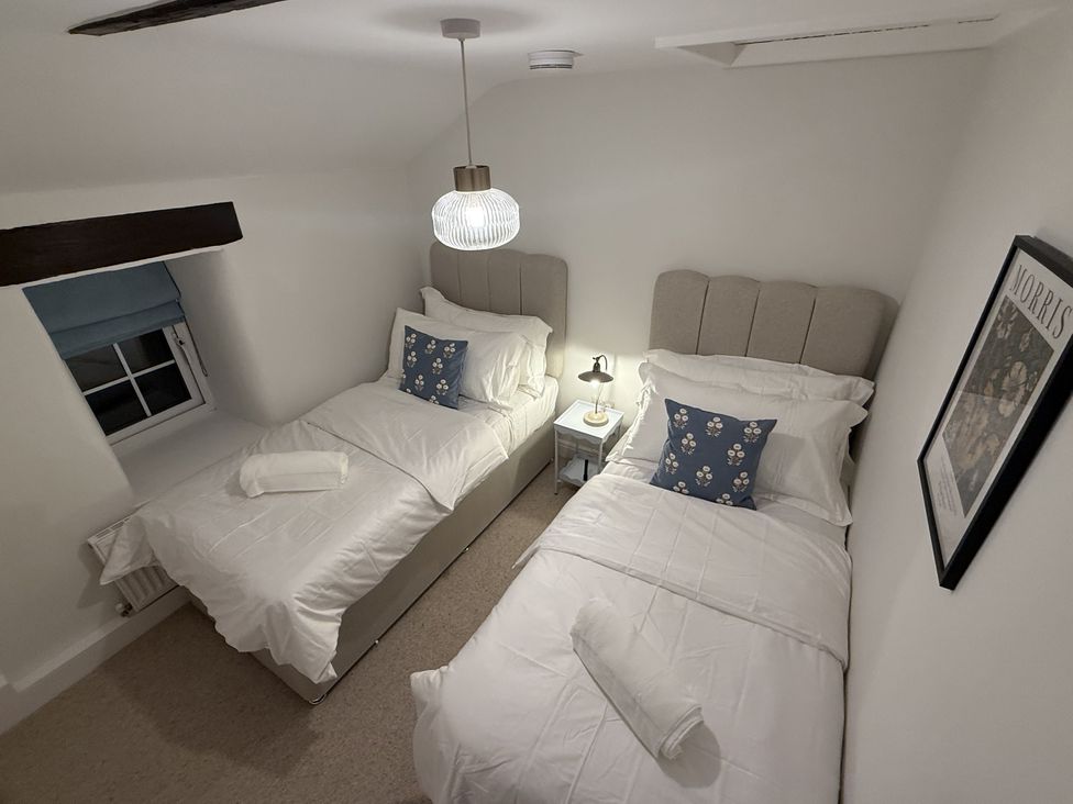A bedroom with two beds and a nightstand at Woodman's Cottage in Newmillerdam