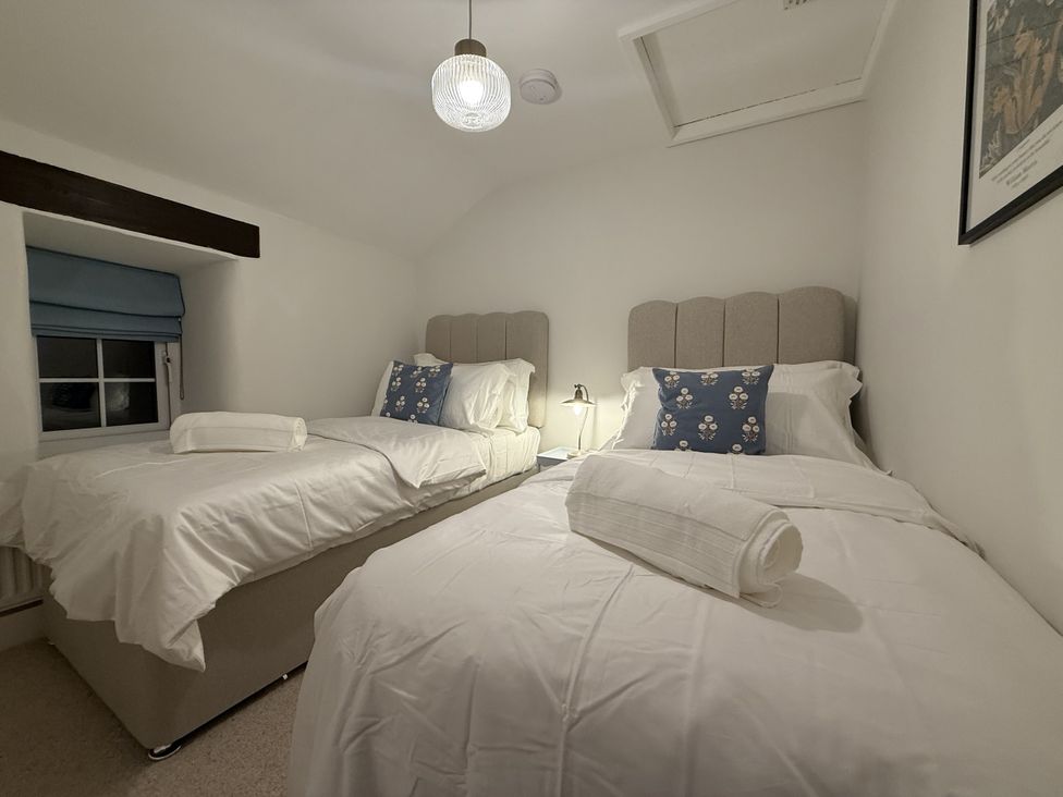A bedroom with two beds and a window at Woodman's Cottage Newmillerdam