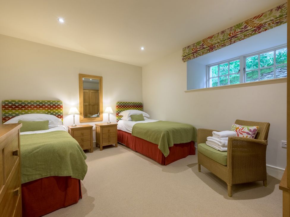 A bedroom with two beds and a chair at The School in Mungrisdale near Caldbeck