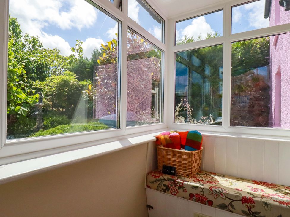 A conservatory with windows and a basket at Brockstone Cottage in St Austell