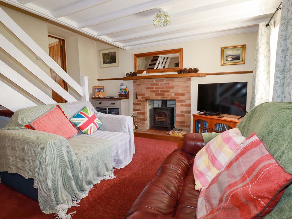 A living room with a fireplace and television at Brockstone Cottage in St Austell