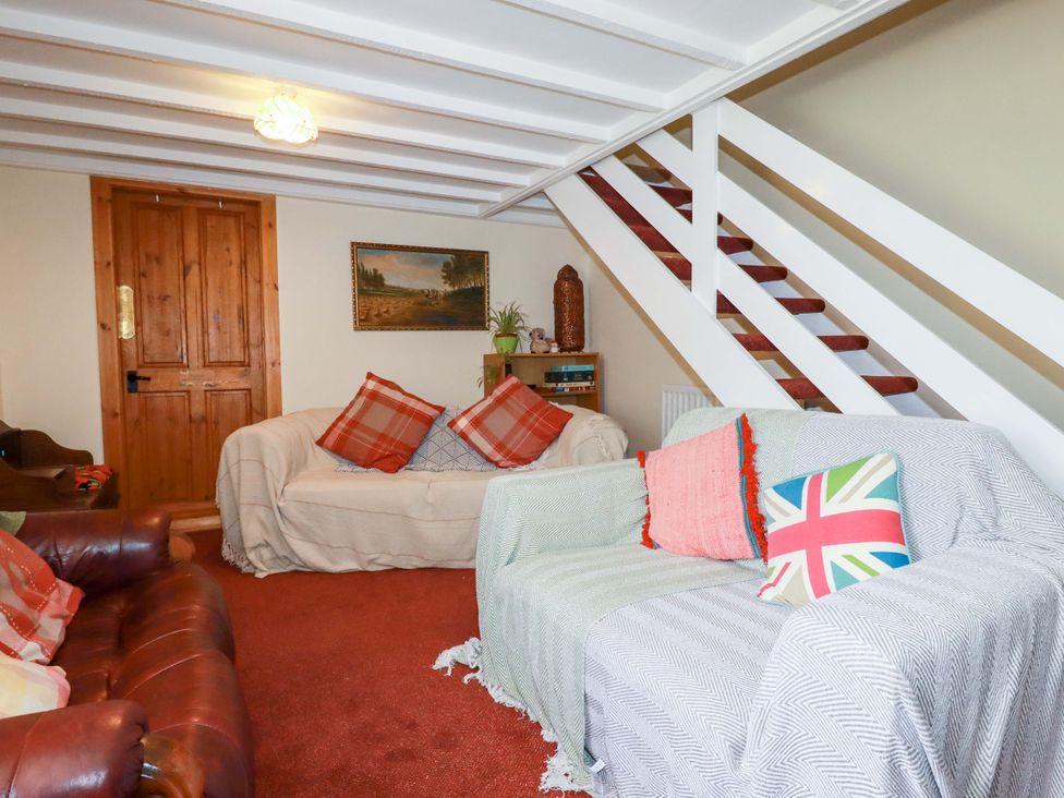 A living room with sofas and a staircase at Brockstone Cottage St Austell