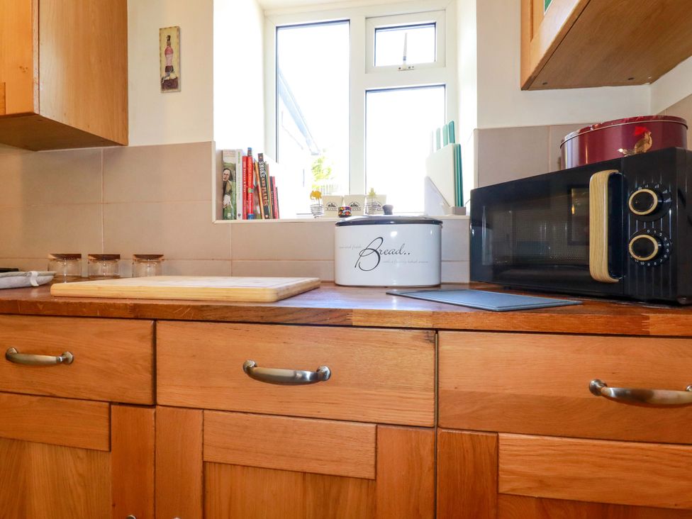 A kitchen with cabinets and a microwave at Brockstone Cottage in St Austell