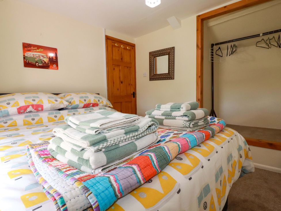 A bedroom with a bed and towels on top at Brockstone Cottage in St Austell