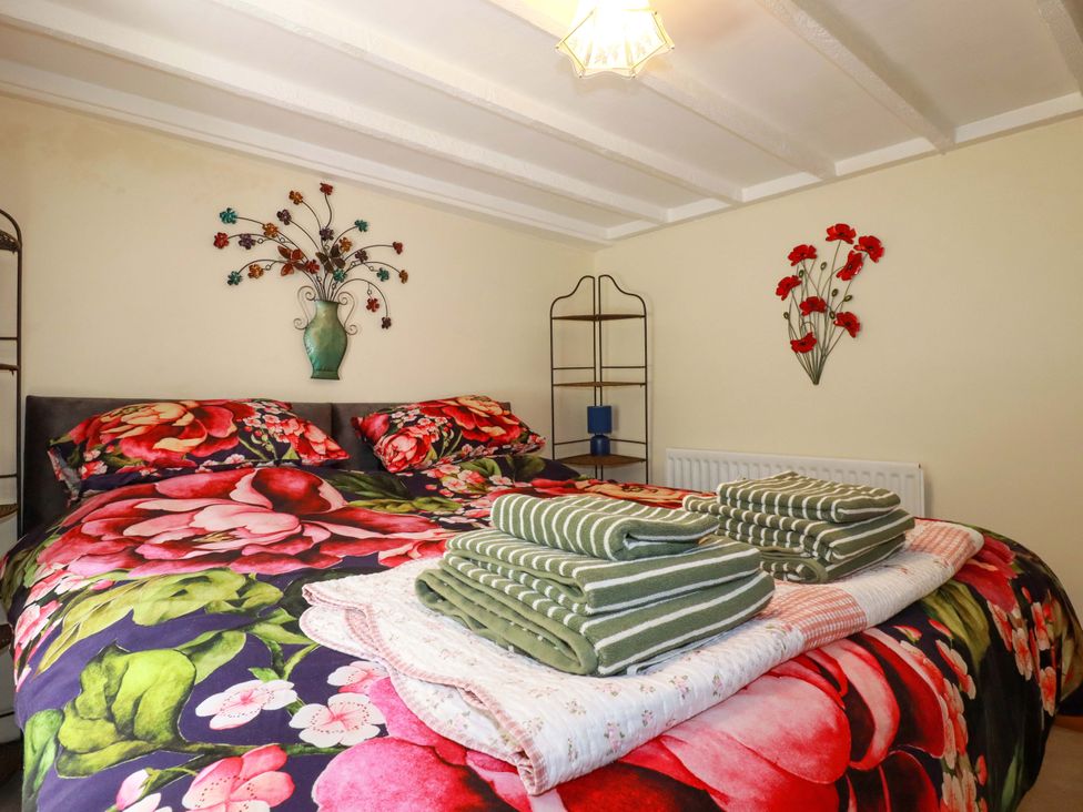 A bedroom with a bed and towels at Brockstone Cottage in St Austell
