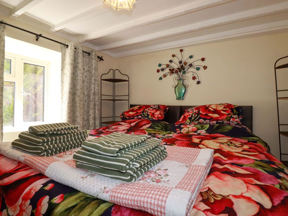 A bedroom with a bed and towels arranged at Brockstone Cottage in St Austell