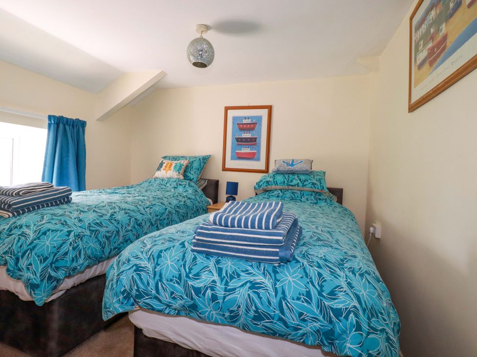 A bedroom with two beds and a picture frame at Brockstone Cottage in St Austell