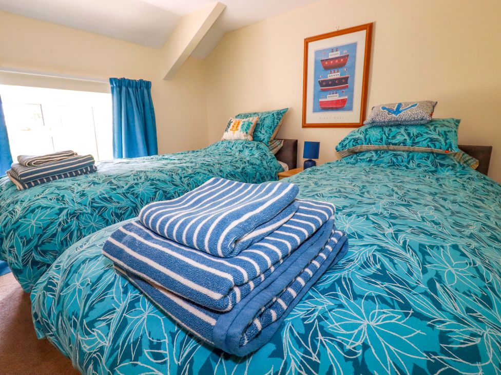 A bedroom with twin beds and towels at Brockstone Cottage St Austell
