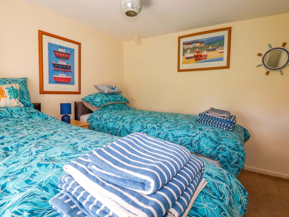A bedroom with twin beds and towels at Brockstone Cottage St Austell
