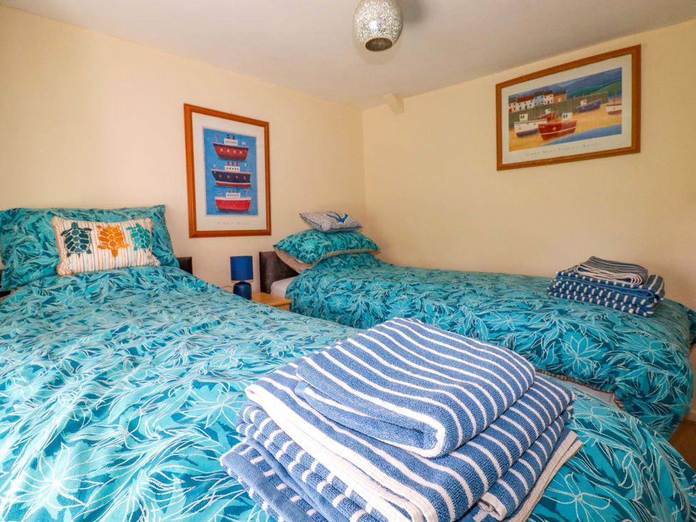 A bedroom with two beds and towels stacked at Brockstone Cottage St Austell