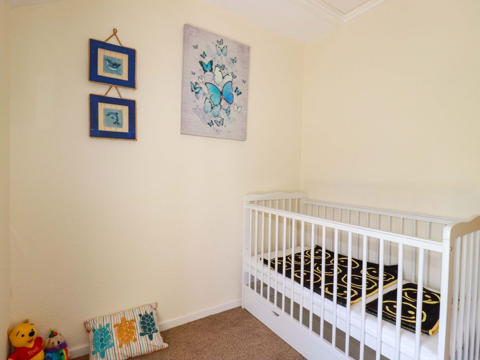A nursery with a crib and decorative items at Brockstone Cottage in St Austell