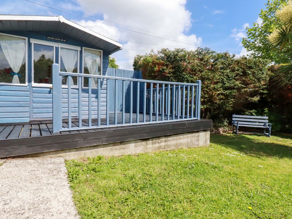 An outdoor deck with cabin and bench at Brockstone Cottage in St Austell