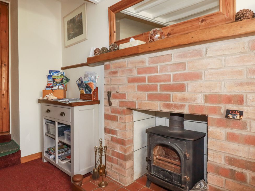 A living room with a fireplace and shelving unit at Brockstone Cottage in St Austell