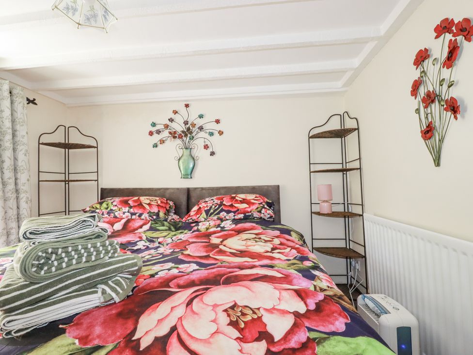 A bedroom with a bed and a shelf at Brockstone Cottage in St Austell