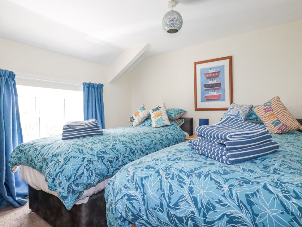 A bedroom with two beds and towels at Brockstone Cottage in St Austell