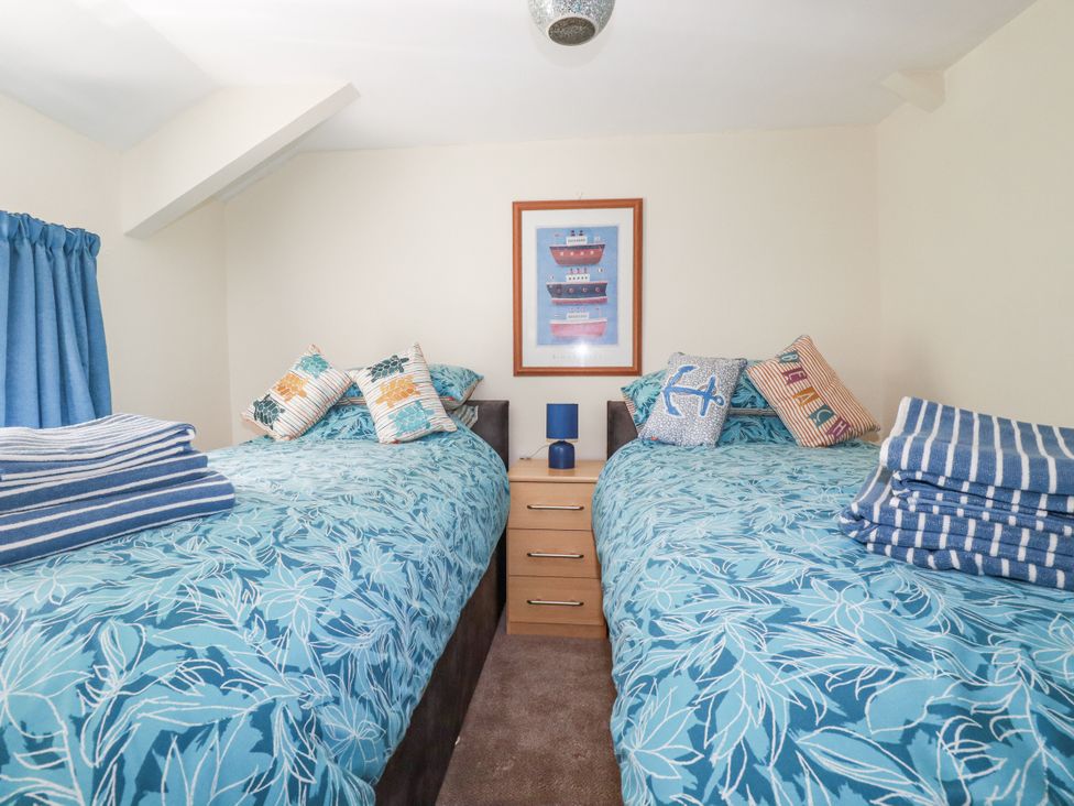 A bedroom with two single beds and a bedside table at Brockstone Cottage in St Austell