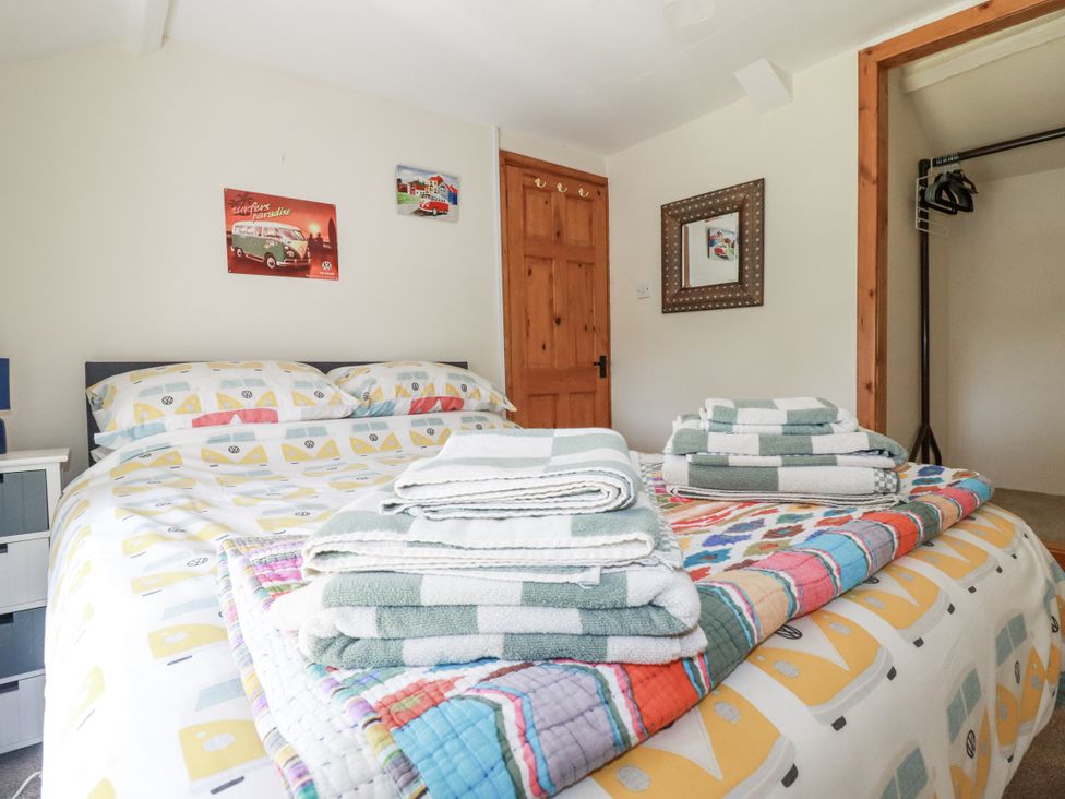 A bedroom with a bed and towels on top at Brockstone Cottage in St Austell
