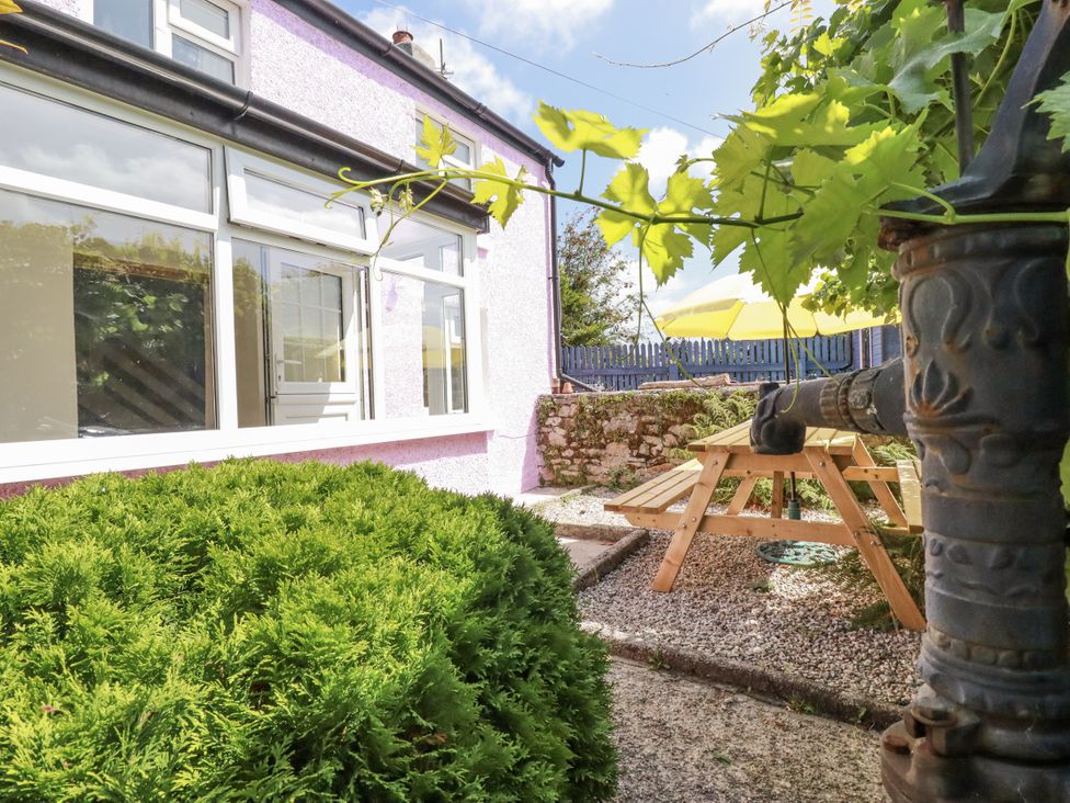A garden with a picnic bench and gravel at Brockstone Cottage in St Austell