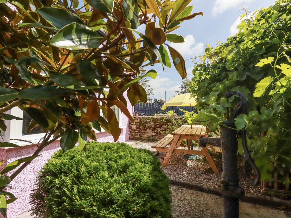 A garden with a wooden table and fountain at Brockstone Cottage in St Austell