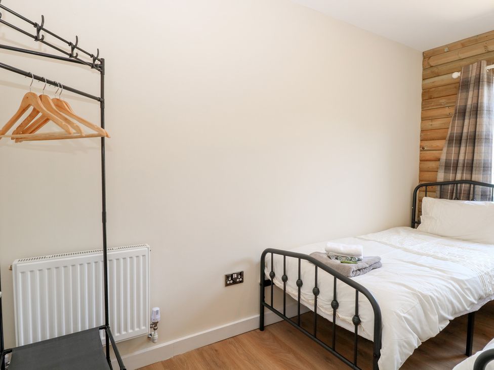 A bedroom with a bed and a clothing rack at Barn Owl Lodge