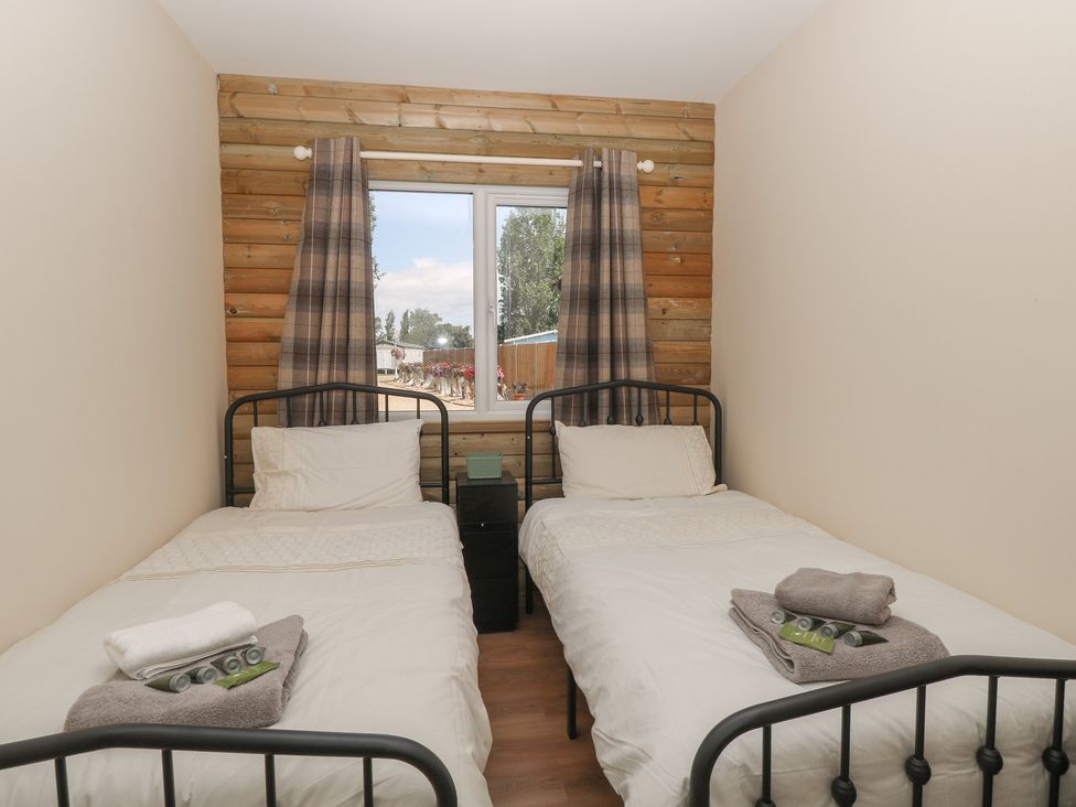 A bedroom with two beds and a window at Barn Owl Lodge