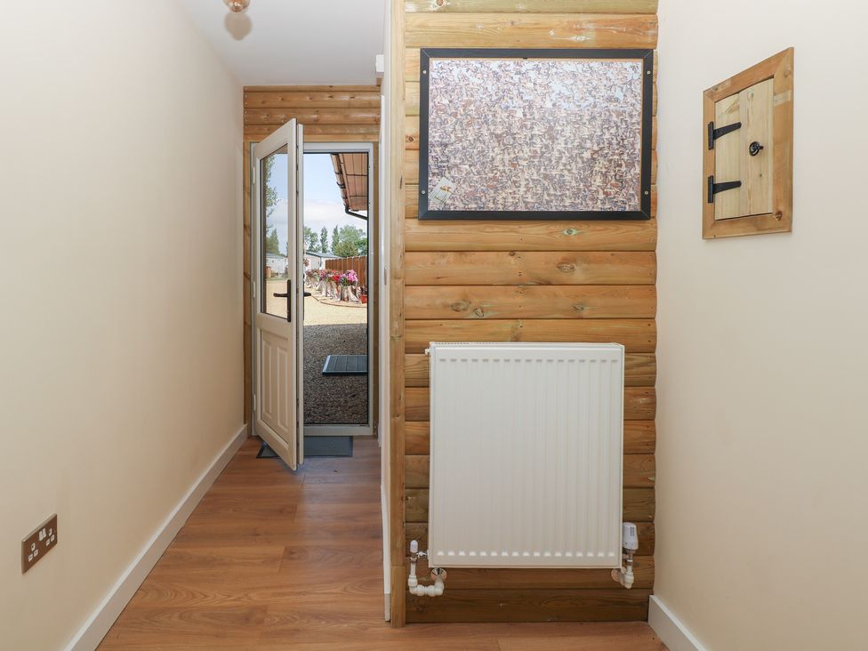 A hallway with a front door and a radiator at Barn Owl Lodge