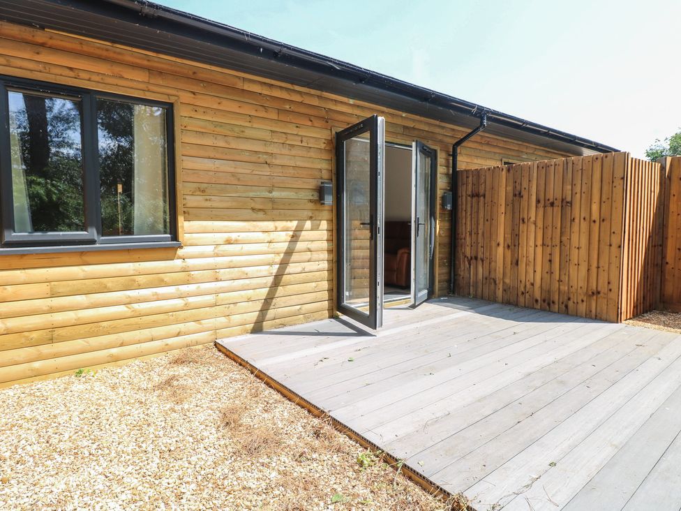 An outdoor area with wooden wall and deck at Barn Owl Lodge