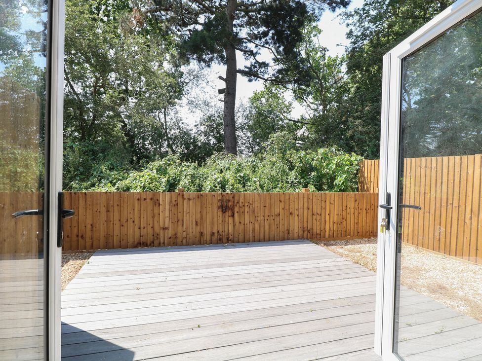 A wooden deck area surrounded by trees at Barn Owl Lodge