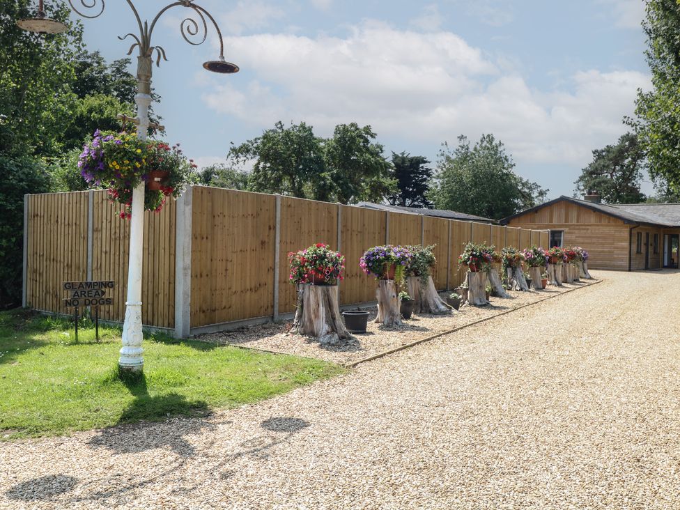 An outdoor glamping area with flower planters and a wooden fence at Barn Owl Lodge