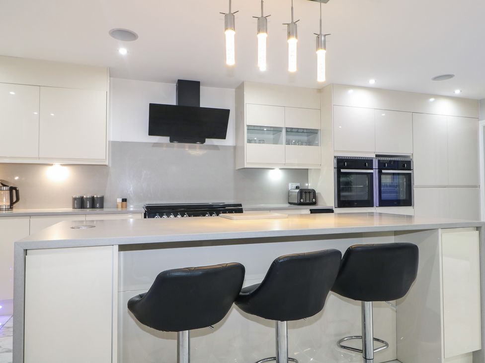 A kitchen with bar stools and appliances at Falcon Bal House