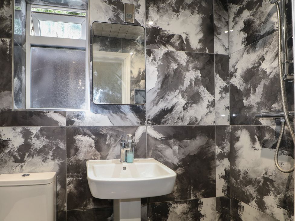 A bathroom with a sink, toilet, shower, mirror, and window at Falcon Bal House