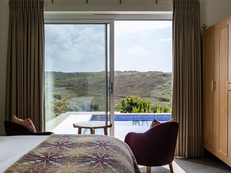 A bedroom with a view of the pool and hills at Trevean in Mullion