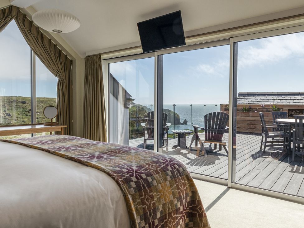 A bedroom with a bed and sliding glass doors at Trevean in Mullion