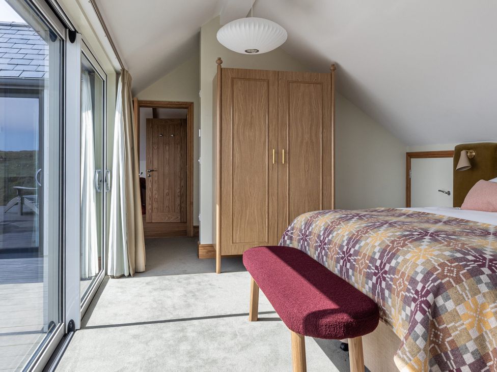 A bedroom with a bed and wardrobe at Trevean in Mullion