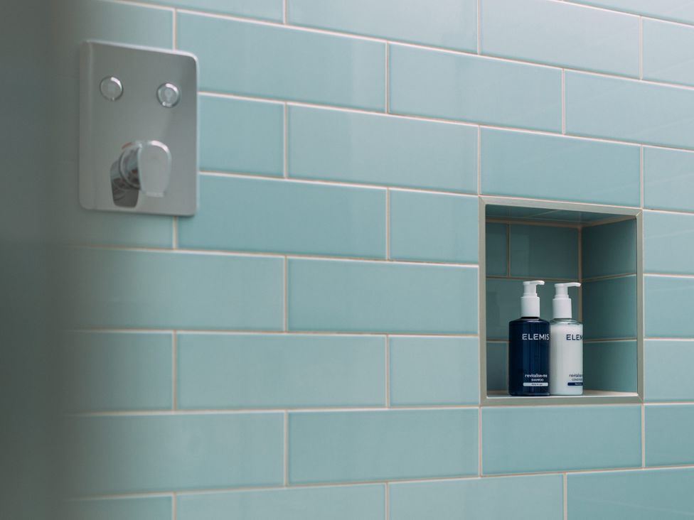 A bathroom with blue tiles and soap dispensers at Trevean in Mullion