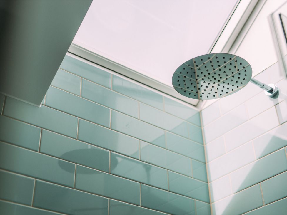 A shower head with tiled walls and a skylight at Trevean in Mullion