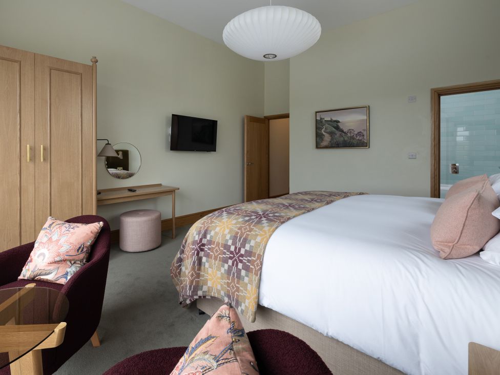 A bedroom with a bed and wardrobe at Trevean in Mullion
