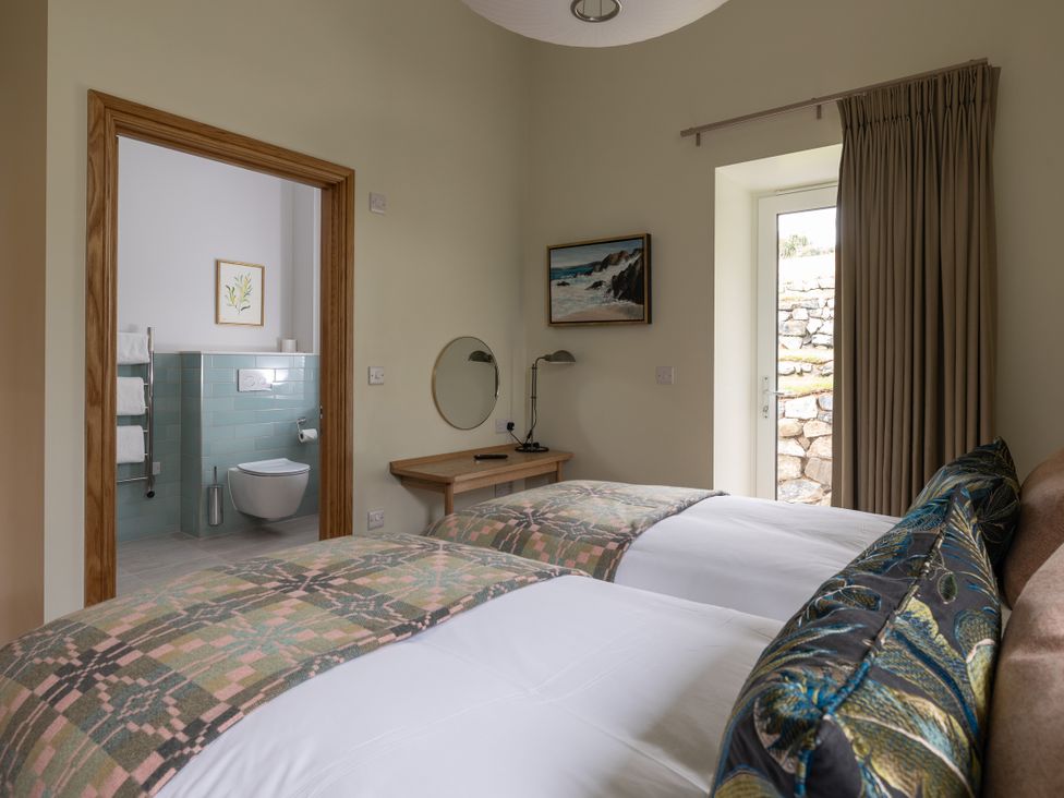 A bedroom with two beds and an en-suite bathroom at Trevean in Mullion
