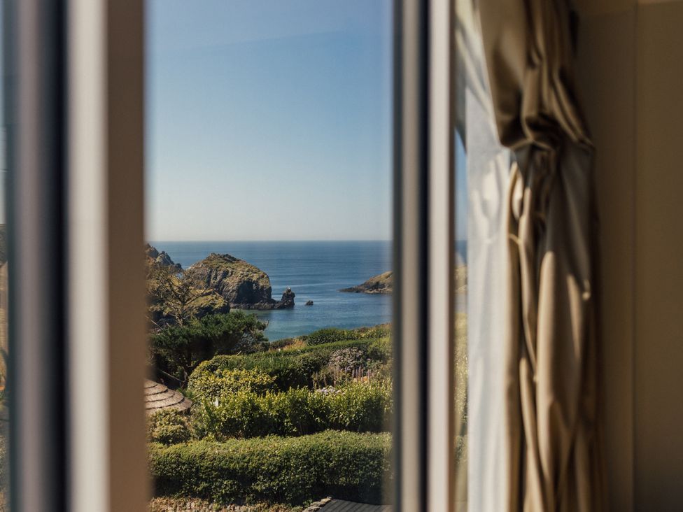 A view of the sea and garden through a window at Trevean in Mullion