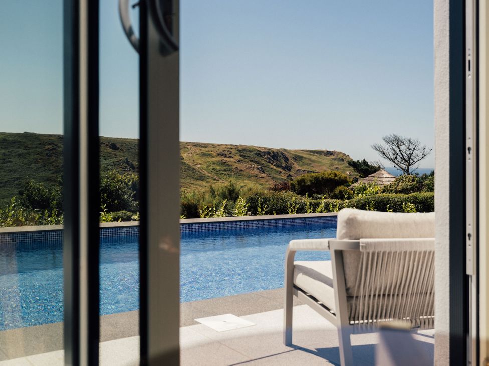 A pool with a chair and hills visible at Trevean in Mullion