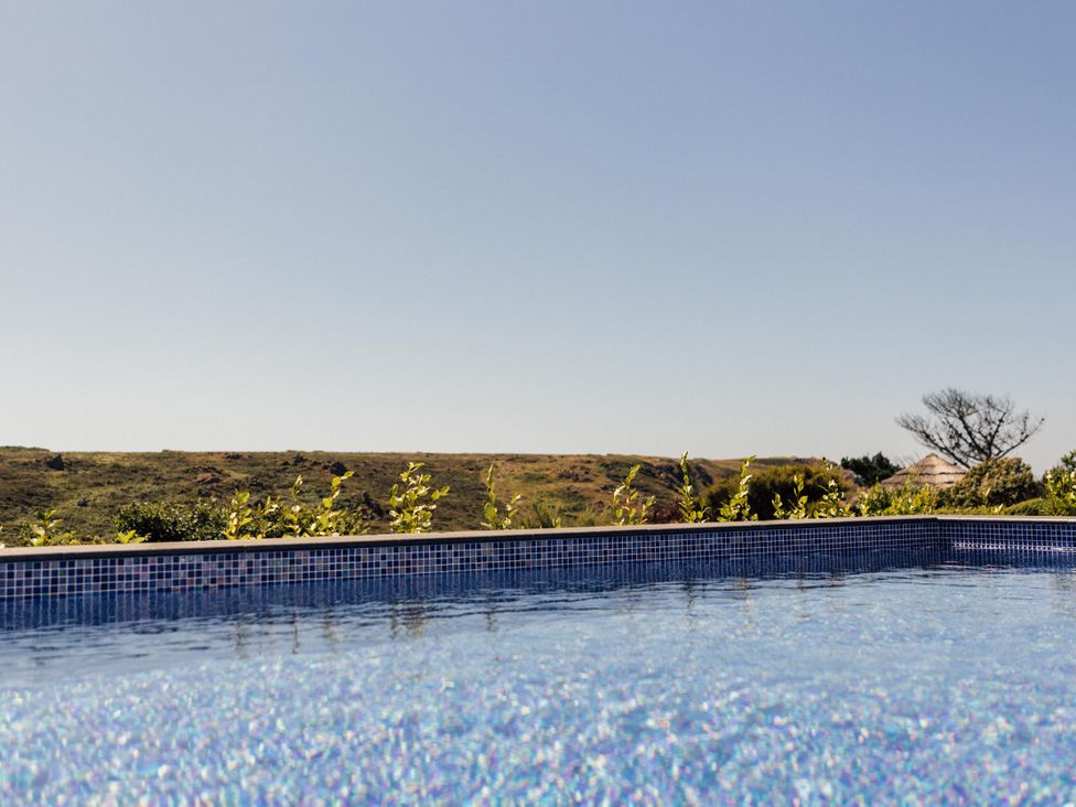 A swimming pool with water and landscape at Trevean in Mullion